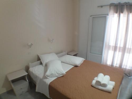 a bedroom with a bed with white pillows and a window at Harbour View - Oceanis Apartments in Poros