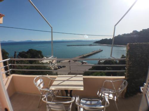 a table and chairs on a balcony with a view of the ocean at Harbour View - Oceanis Apartments in Poros