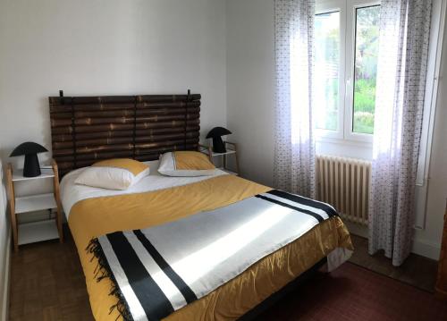 une chambre avec un lit avec une tête de lit en bois et une fenêtre dans l'établissement COTTAGE des RIAS 2 chambres d'hôtes ou 1 suite à 172 m de la mer sans TV, à Kerfany-les-Pins