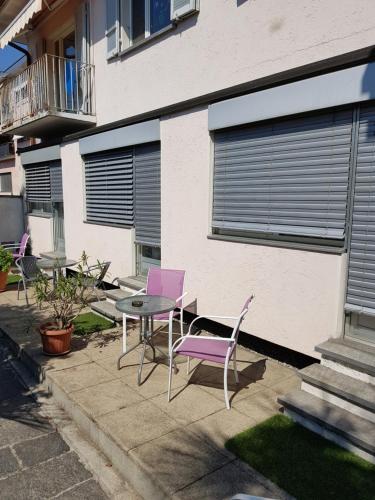 a group of purple chairs and a table in front of a building at Garni Elisabetta in Gordola