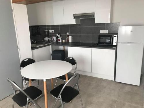 une cuisine avec une table, des chaises et un réfrigérateur dans l'établissement appartement neuf P3 50m2, à Nîmes