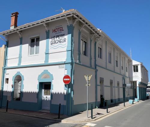 a white and blue building on the corner of a street at Hotel Le Petit Baigneur Palavas Plage in Palavas-les-Flots