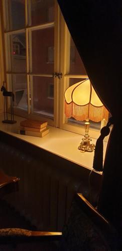 Leopold Boutique Hotel في أوسترسوند: مصباح جالس على طاولة بجوار النافذة