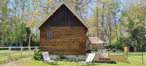 a wooden cabin with two chairs and a table at La Cabane de Fierville in Fierville-les-Parcs
