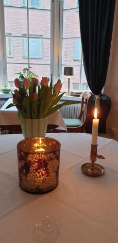 a candle and a vase with flowers on a table at Leopold Boutique Hotel in Östersund