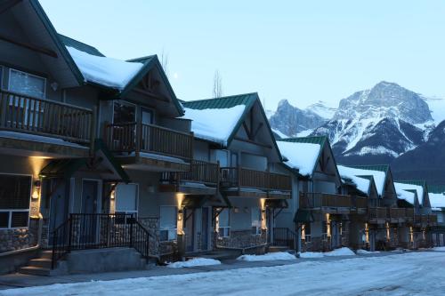 a row of buildings with snow covered mountains in the background at Banff Woods lodge in Canmore