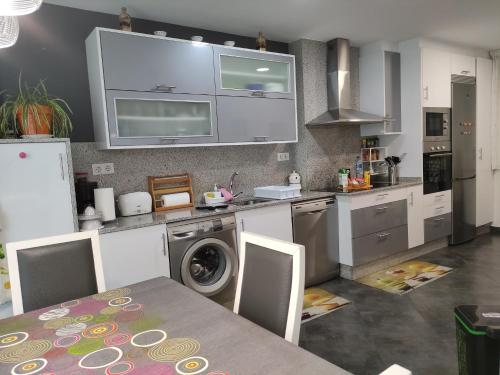 eine Küche mit einer Waschmaschine und einem Tisch mit Stühlen in der Unterkunft Piso torre in A Coruña