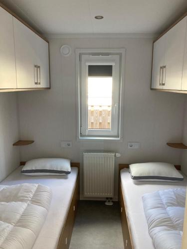 two beds in a room with a window at Chalet Mariënberg in Mariënberg