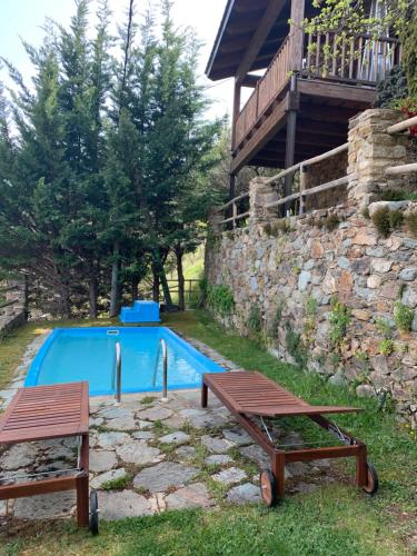 a swimming pool with two picnic tables next to a building at Casa Rural Pirineu Nevà in Nevà