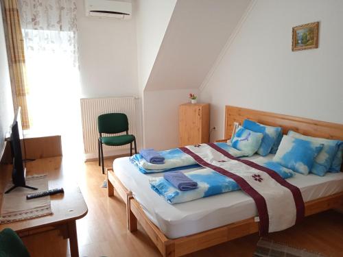 a bedroom with a bed with blue pillows and a desk at Agria Wellness Guesthouse in Eger