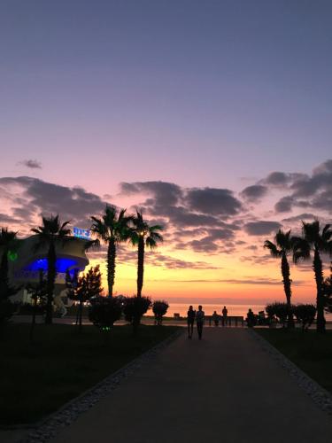 巴统Downtown Batumi apartment的一群人日落时分沿着人行道走下