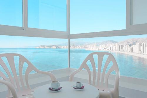 two white chairs and a table with cups on it at KAKTUS Hotel Benikaktus in Benidorm
