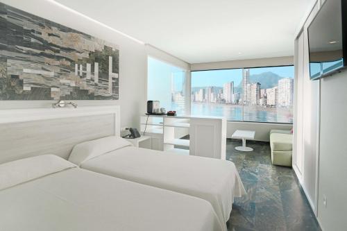 a bedroom with two beds and a large window at Hotel Benikaktus in Benidorm