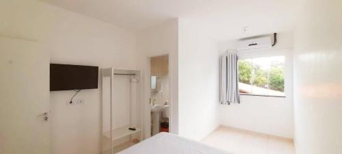 a white room with a bed and a window at Pousada Pontal do Sul in Pontal do Paraná