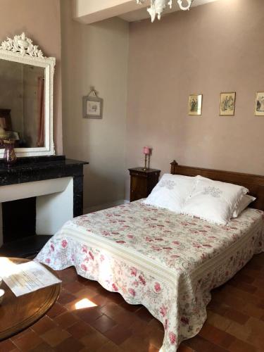 a bedroom with a bed with a table and a fireplace at Le Sillon d'Alaric in Lézignan-Corbières