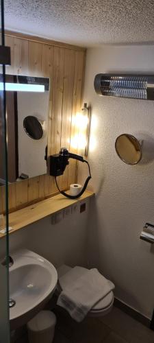 a bathroom with a sink and a mirror and a toilet at The Originals Access, Hôtel Foix in Foix
