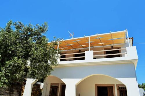 a white house with a tree in front of it at Meltemi Appartment in Patitiri