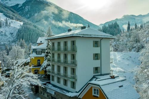 um grande edifício branco com neve no telhado em Nefer, Haus em Bad Gastein