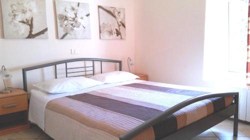 1 dormitorio con 1 cama con sábanas blancas y cuadros en la pared en Apartment Ivan, en Pula