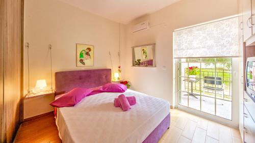 een slaapkamer met een bed met roze lakens en een raam bij Villazia Exclusive Estate in Episkopianá