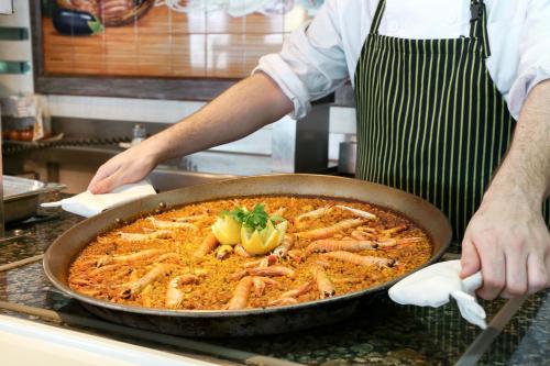 a person in a kitchen preparing food in a pan at KAKTUS Hotel Benikaktus in Benidorm