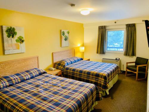a hotel room with two beds and a chair at Green Acres Motel in Mississauga