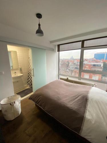 a bedroom with a large bed and a large window at Brussels By Night panoramic studio apartment for 2 in Brussels