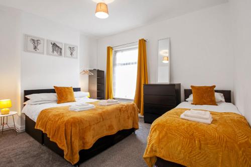 1 dormitorio con 2 camas con sábanas de color naranja y ventana en Staywhenever LS- 4 Bedroom House, King Size Beds, Sleeps 9, en Stoke on Trent