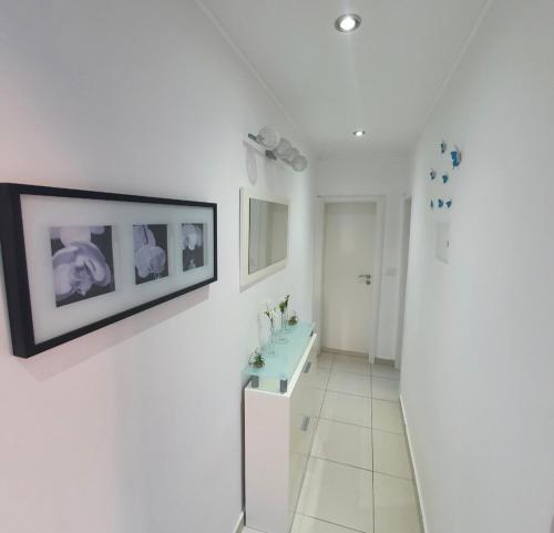 a white bathroom with a sink and a picture on the wall at Apartman Noa in Jadrija