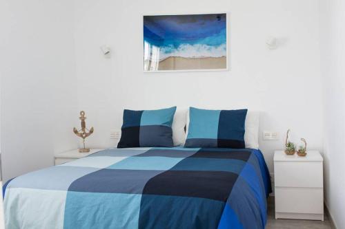 niebiesko-białe łóżko w białej sypialni w obiekcie Apartamento Aguaviva, tu lugar al lado del Océano w Costa Teguise