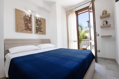 a bedroom with a blue bed and a window at Sea Vito Apartment in San Vito lo Capo