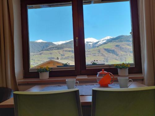 a table with two chairs and a window with mountains at Appartement Anneke in Niedernsill