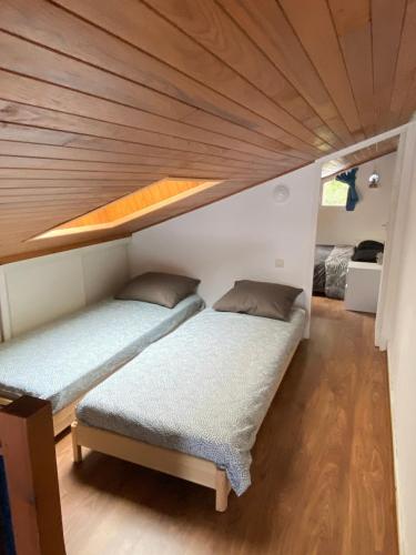Cette petite chambre dispose de 2 lits et d'un plafond en bois. dans l'établissement Maison de la mer, à Hendaye