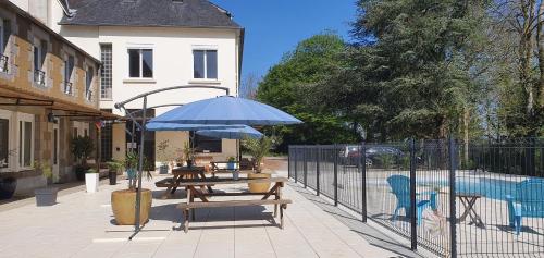 a picnic table with a blue umbrella on a patio at Cosy Er Lann Gîte Séquoïa in Val Couesnon