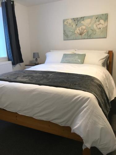 a bedroom with a large bed with white sheets at 2 bedroom apartment in Plymouth