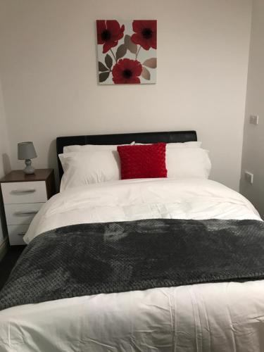 a bedroom with a white bed with a red pillow at 2 bedroom apartment in Plymouth