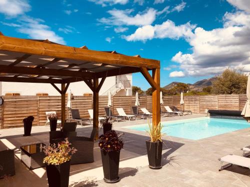 un patio con piscina y pérgola de madera en Résidence Casa Toga en Galeria