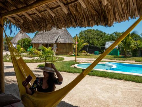 a woman sitting in a hammock by a pool at Cabanas Jaalkab in Chelem