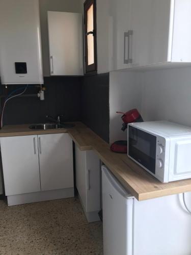 une cuisine avec des placards blancs et un four micro-ondes sur un comptoir dans l'établissement Appartement st Pierre la mer, à Fleury