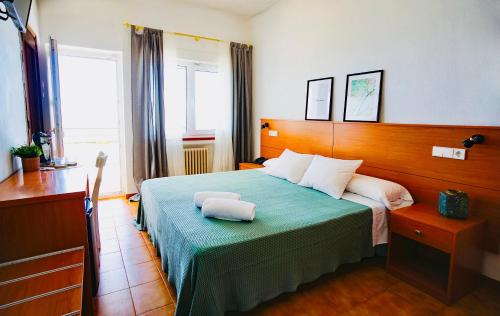 a bedroom with a bed with two towels on it at Hotel Patricia in Torreguadiaro
