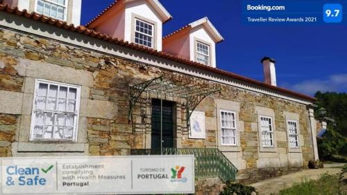 un bâtiment en pierre avec un panneau en face de celui-ci dans l'établissement Casa do Hospital-Guest House, à Abaças