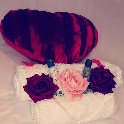 a heart shaped pillow and three roses on a towel at Twenty4ten Guesthouse in Gaborone