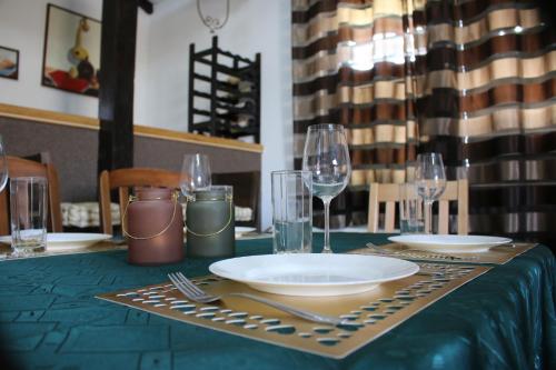 a table with plates and glasses on a green table at House Milovanovic in Soko Banja