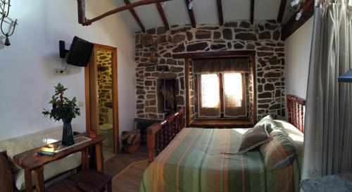 1 dormitorio con cama y pared de piedra en Casa Miguel, en Olea