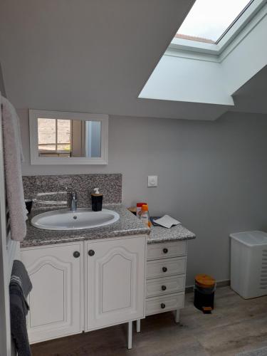 a bathroom with a sink and a skylight at Gîte de la Pierre percée in Roôcourt-la-Côte