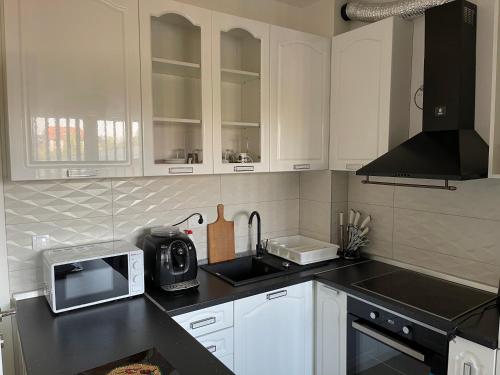 a kitchen with white cabinets and a sink and a microwave at Royal Residence Apartmani in Pančevo