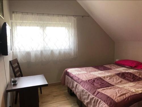 a bedroom with a bed and a table and a window at Apartament Leśna Ostoja Rychwałd in Rychwałd