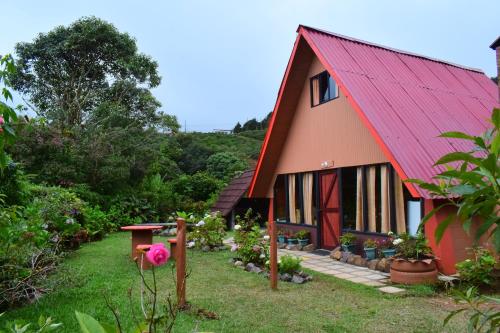 a red house with a red roof and some plants at Reserva Natural Cerro Alto in Empalme