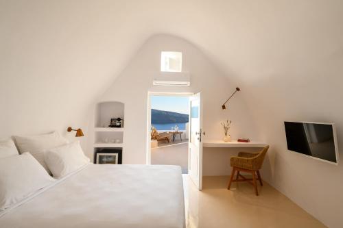 una camera con letto, scrivania e TV di Canvas Suites a Oia