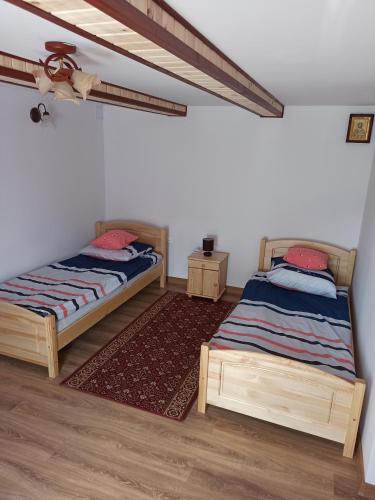 DobrowodyにあるAgroturystyka Leśny Zakątekの白い壁とウッドフロアの客室で、ベッド2台が備わります。
